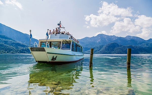 Bei einer Schifffahrt auf dem Kochelsee können Besucher die Wasserkulisse noch einmal aus einer anderen Perspektive genießen – und nebenbei verschiedene Ziele problemlos erreichen. (Foto: epr/Thomas Kujat/Tourist Information Walchensee)