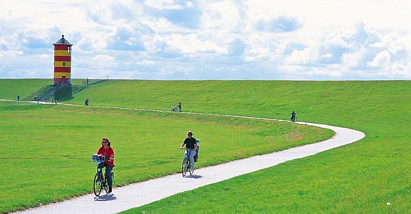 Der gelbrot geringelte Pilsumer Leuchtturm grüßt die Radler auf dem Nordsee-Radweg. Foto: djd/TourismusMarketing Niedersachsen