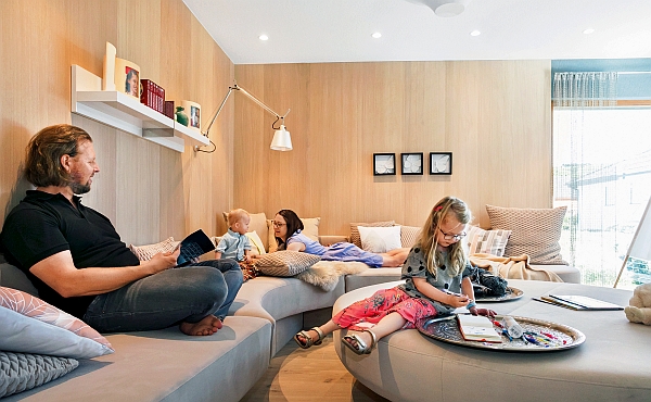Die kuschelige und großzügige Couchlandschaft im Wohnzimmer bietet Platz für jedes Familienmitglied. Holzverkleidete Wände runden das gemütliche Ambiente ab und strahlen behagliche Natürlichkeit aus. (Foto: epr/SchwörerHaus)